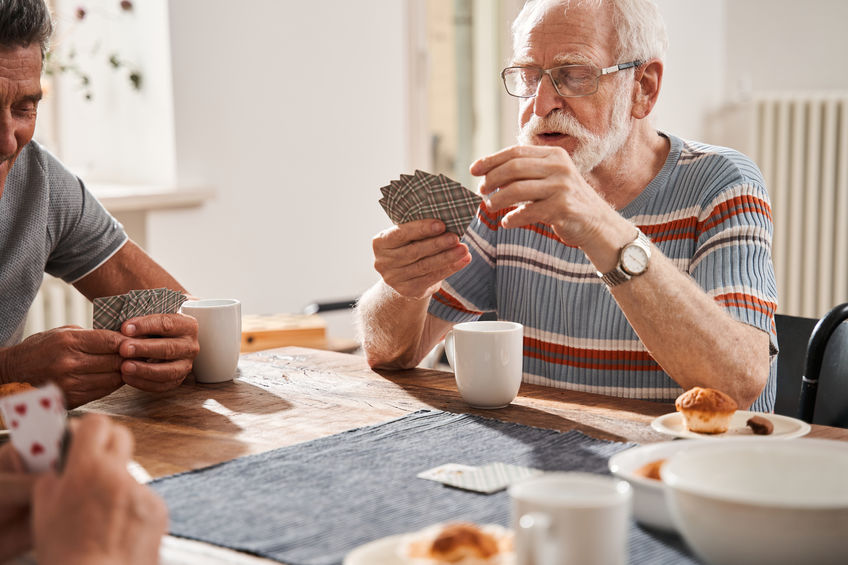 The Advantages of Independent Living for Senior Citizens Senior man playing at the cards with his friends at independent living place for seniors